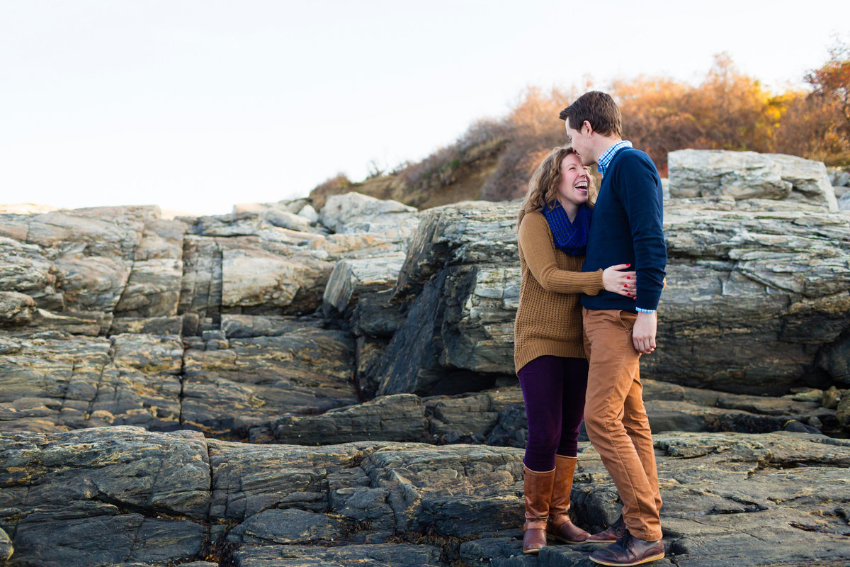 In Cape Elizabeth at Fort Williams the couple laughs on the rocks at their engagement session