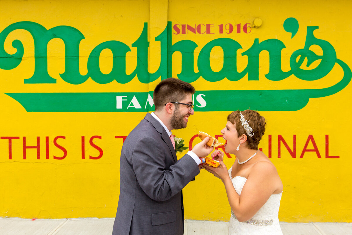 A bride and groom sharing a hot dog.