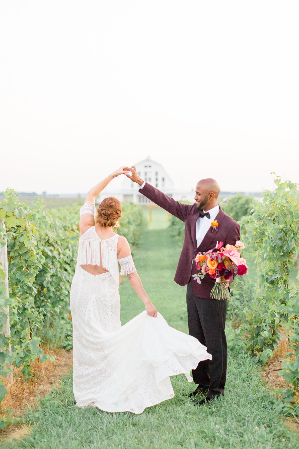 Groom spins his bride between rows of vineyard on their wedding day