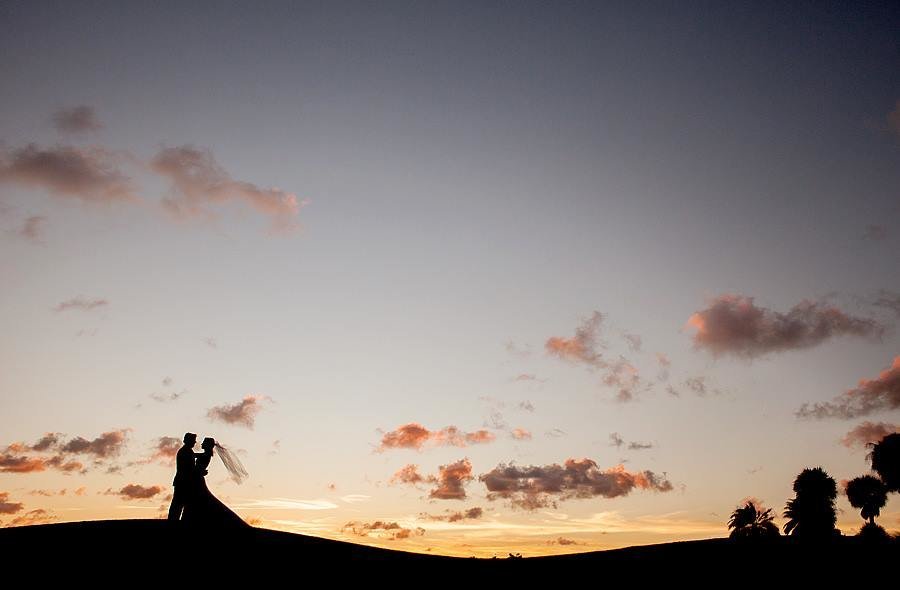Couple standing on hill at sunset