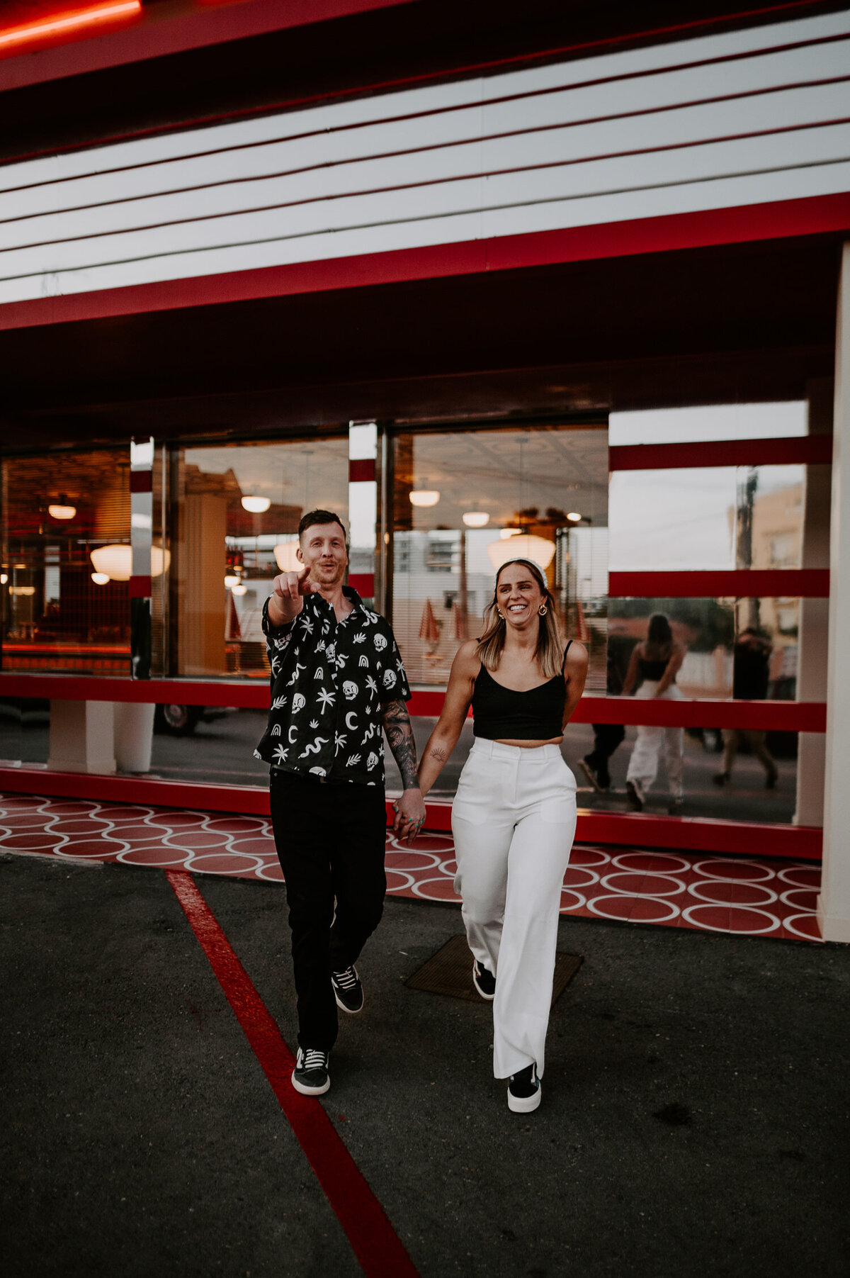 A couple walk towards the camera outside Romeos' Motel and Diner in Ibiza. The Diner has a Las Vegas style vibe.