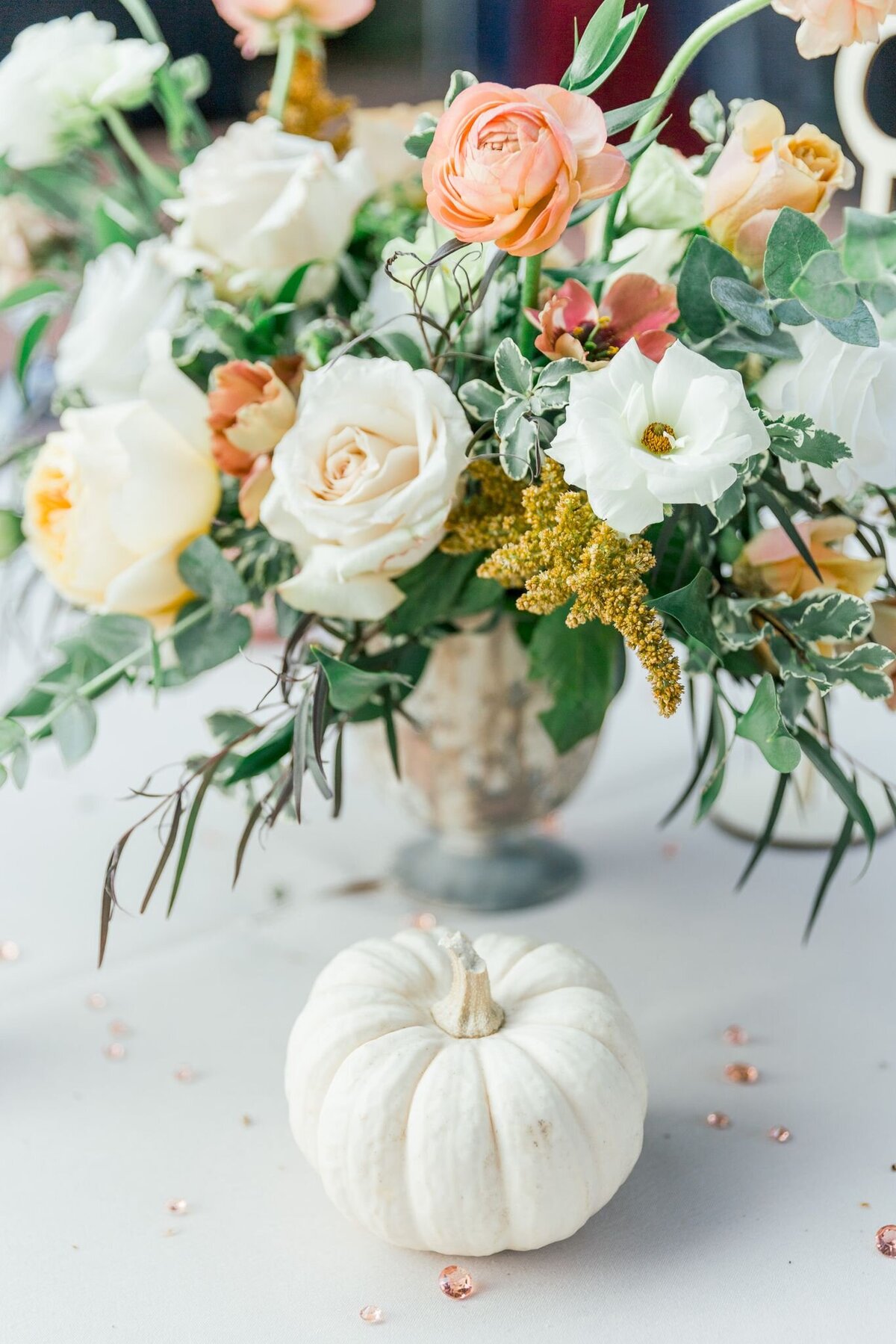 This bouquet screams fall and is placed next to a mini white pumpkin.