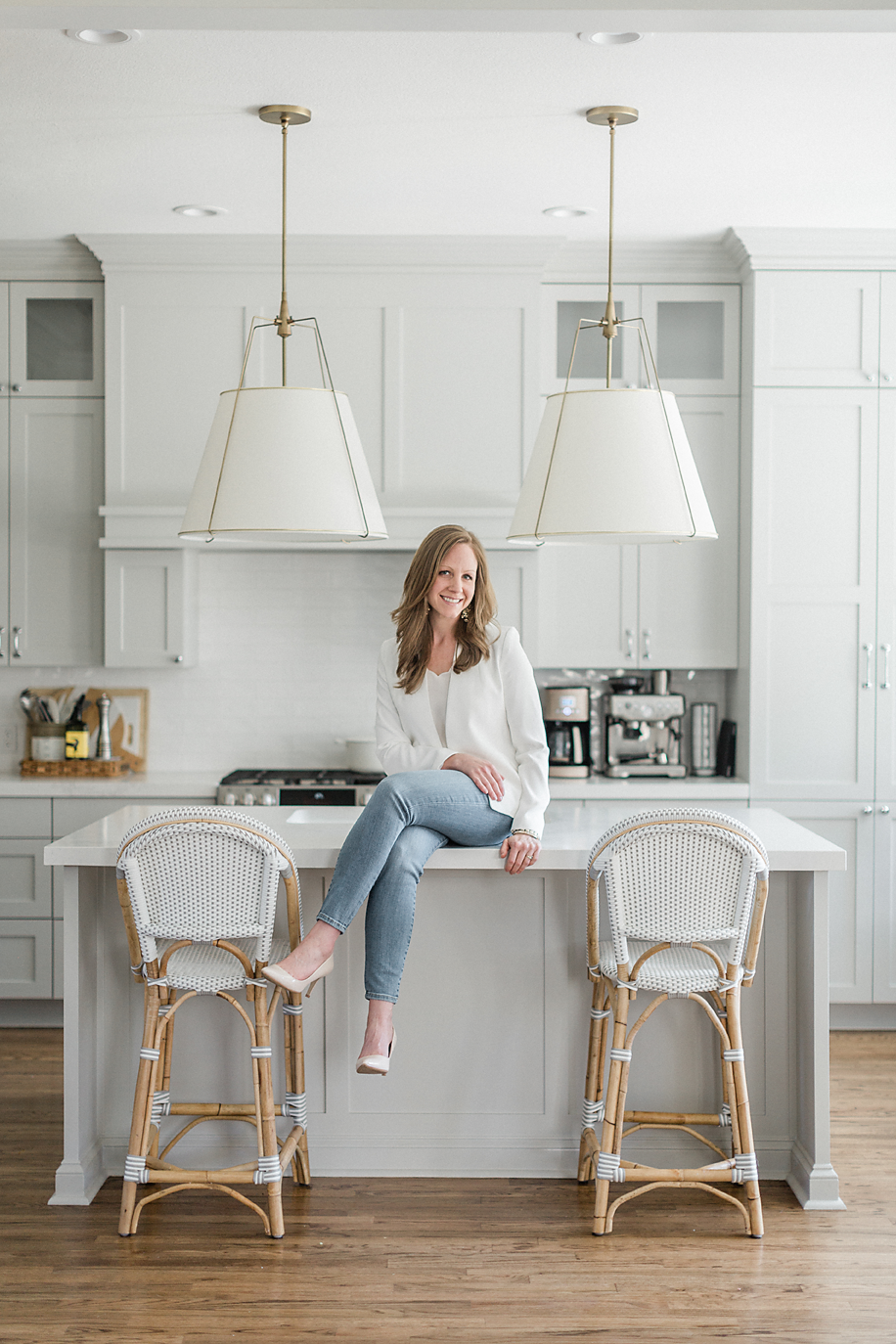 Professional headshot photo of a Dallas Texas business woman posing on a kitchen island counter of a beautifully designed kitchen as she smiles at the camera for her branding/headshot session.