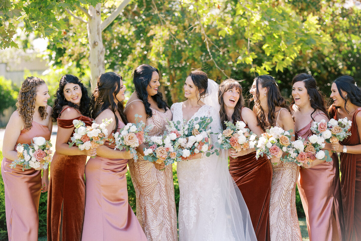 bride and bridesmaids in different orange dresses