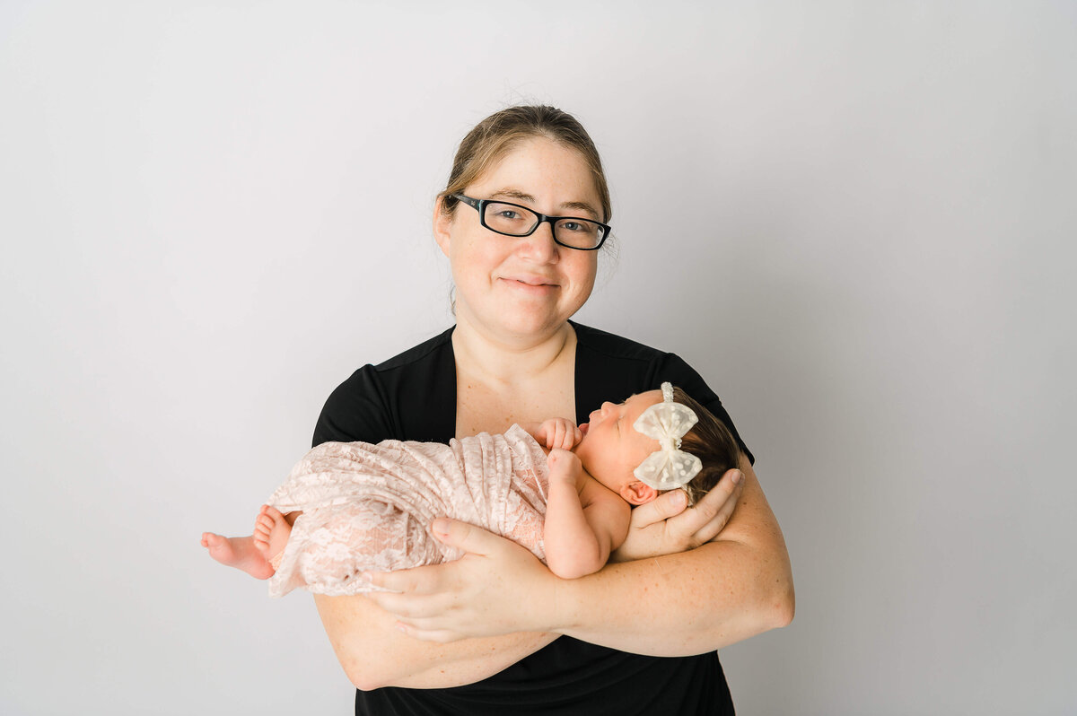 An Edmonton mom holdinig her newborn baby girl wrapped in pink lace swaddle