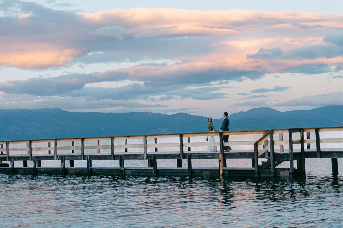 couple walking on a pier in lake tahoe during sunset