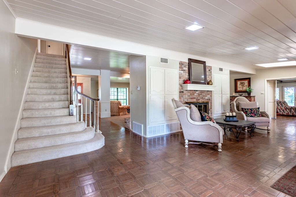 Beautiful staircase and open concept living room with comfortable seating in this 5-bedroom, 4-bathroom vacation rental house for 16+ guests with pool, free wifi, guesthouse and game room just 20 minutes away from downtown Waco, TX.