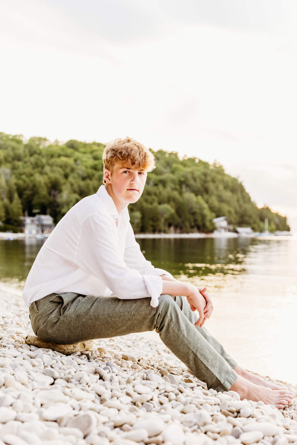 boy sitting on a white rock beach at sunset