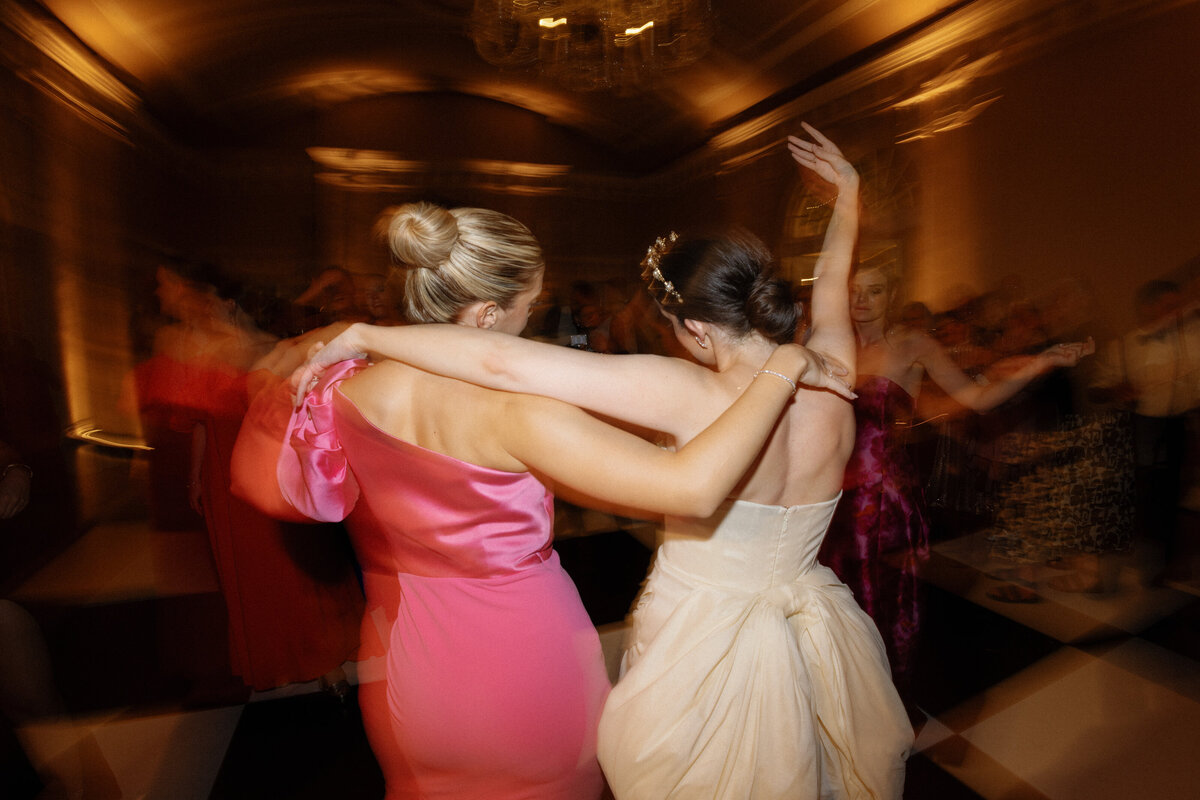 Bride dancing with wedding guest in pink dress