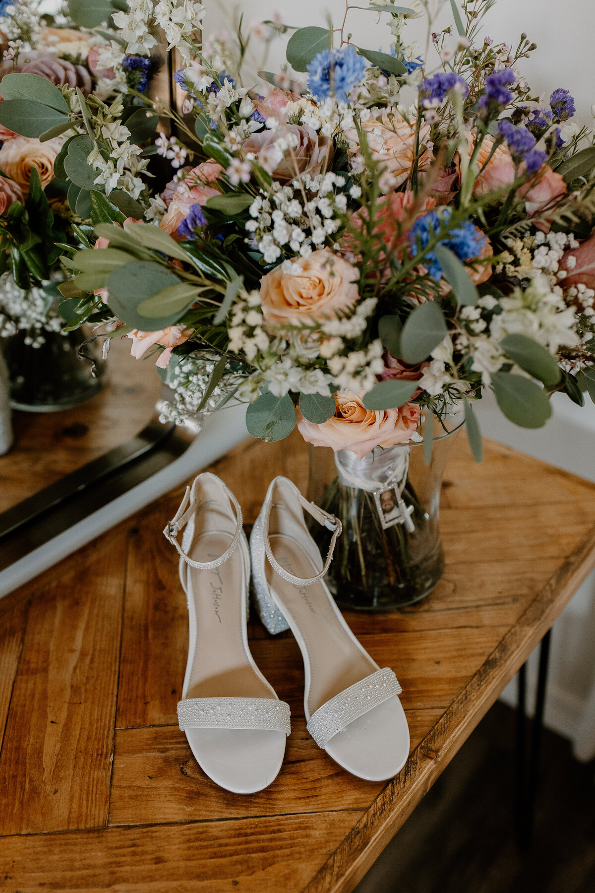 white heels sitting on a table next to a bouquet of flowers.