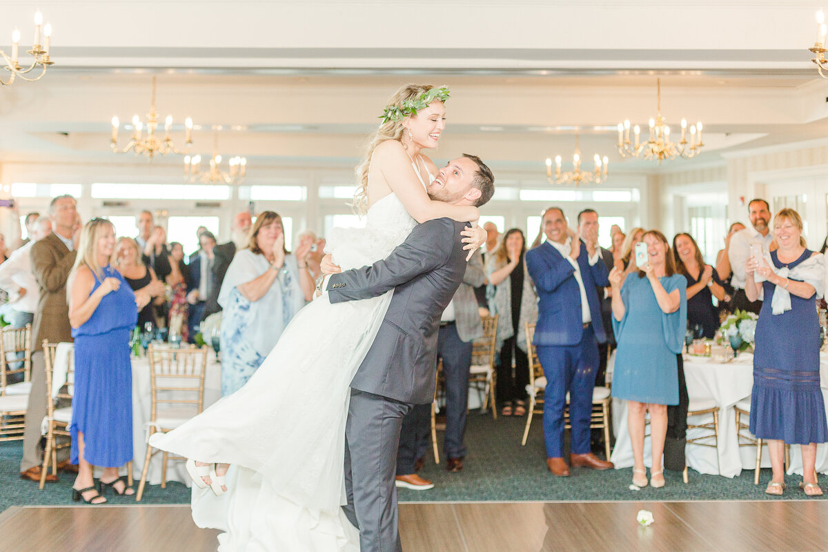 Bride and groom share a first dance at their Madison Beach Hotel wedding. The groom is lifting up his bride and they are looking at each other laughing. Captured by Lia Rose Weddings