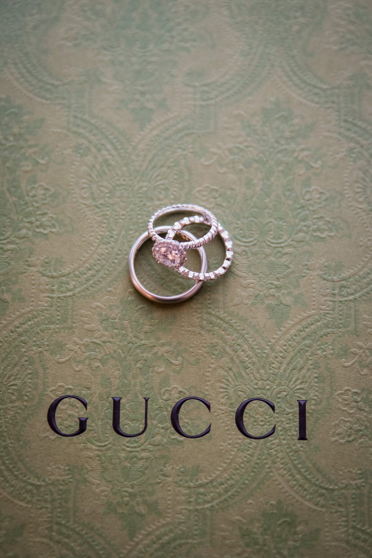 A set of wedding rings sits on a Gucci shoe box.