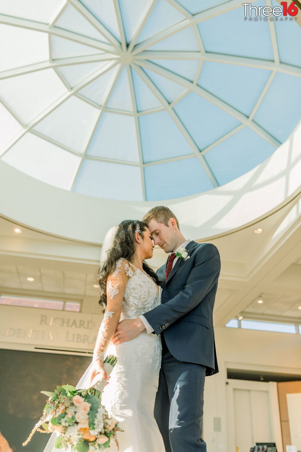 Bride and Groom embrace one another in the Richard Nixon Library lobby area