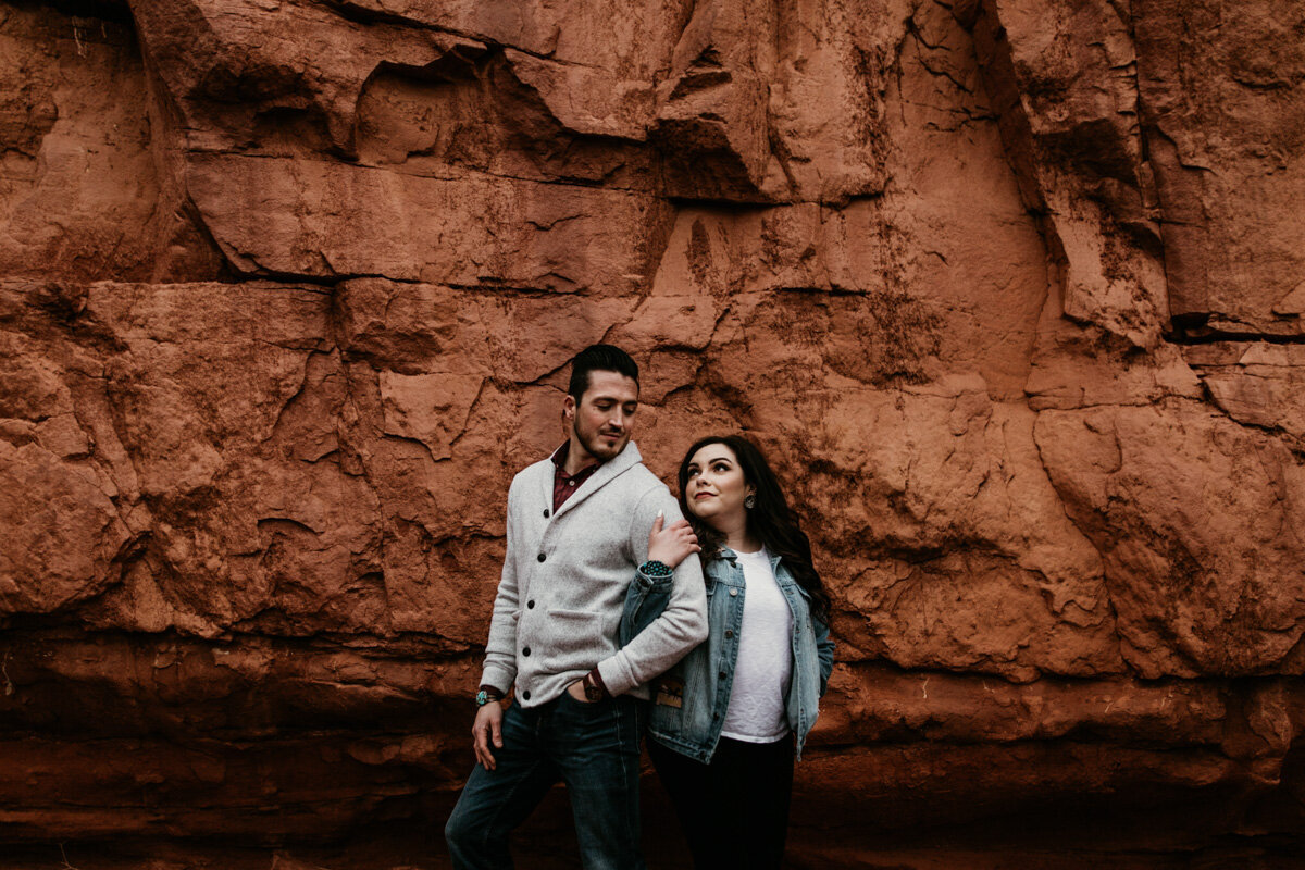 woman holding mans arm in front of red rocks