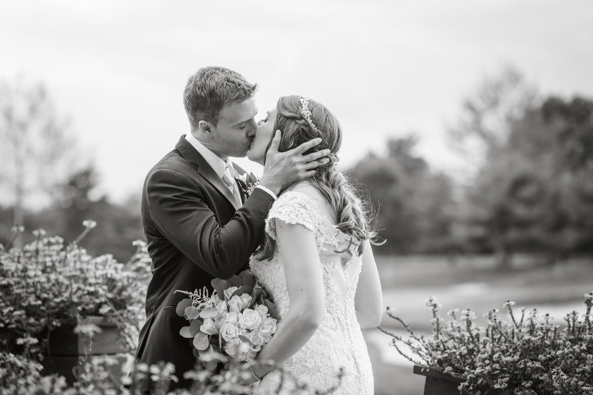 black and white photo of bride and groom kissing on golf course at Willow Creek Golf and Country Club