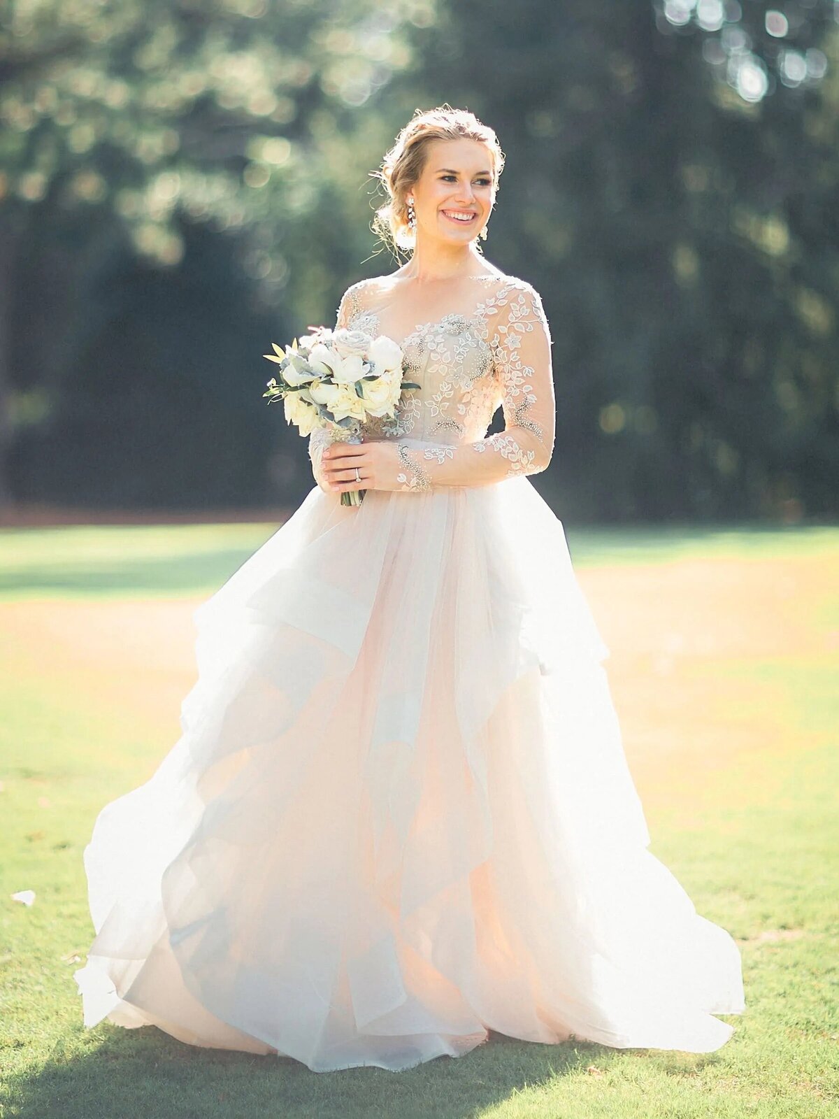 A bride smiling and looking off to the side while holding a bouquet