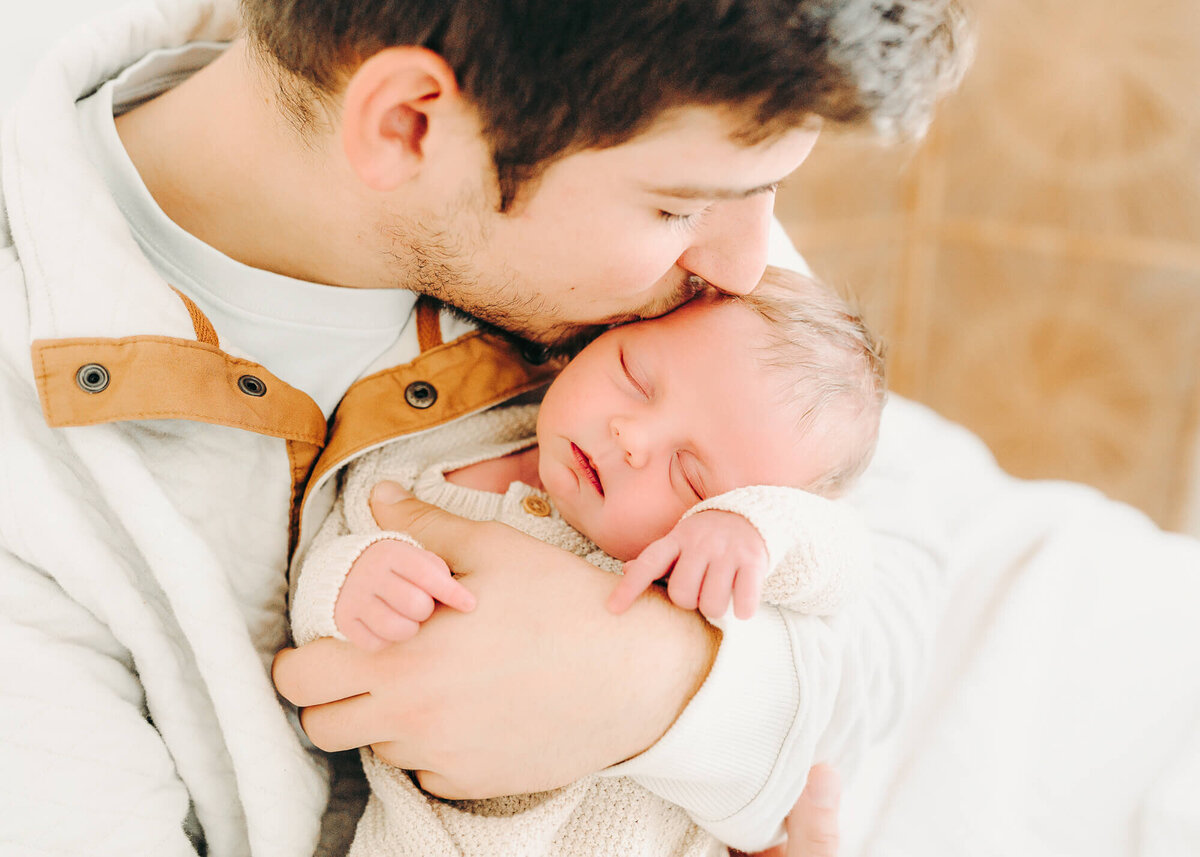 dad kisses  baby for newborn photos in jackson missouri