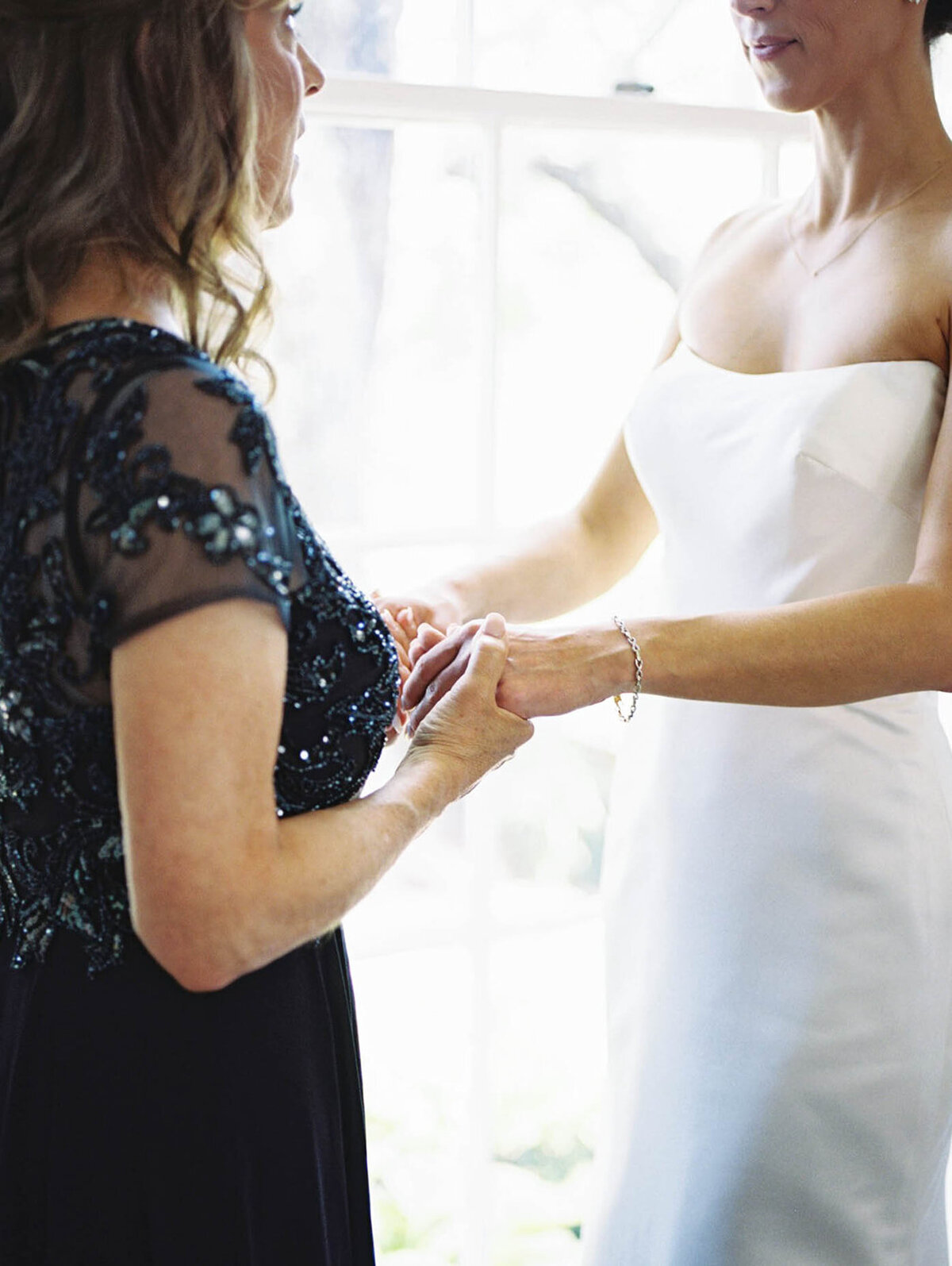 Bride and mom embrace hands together