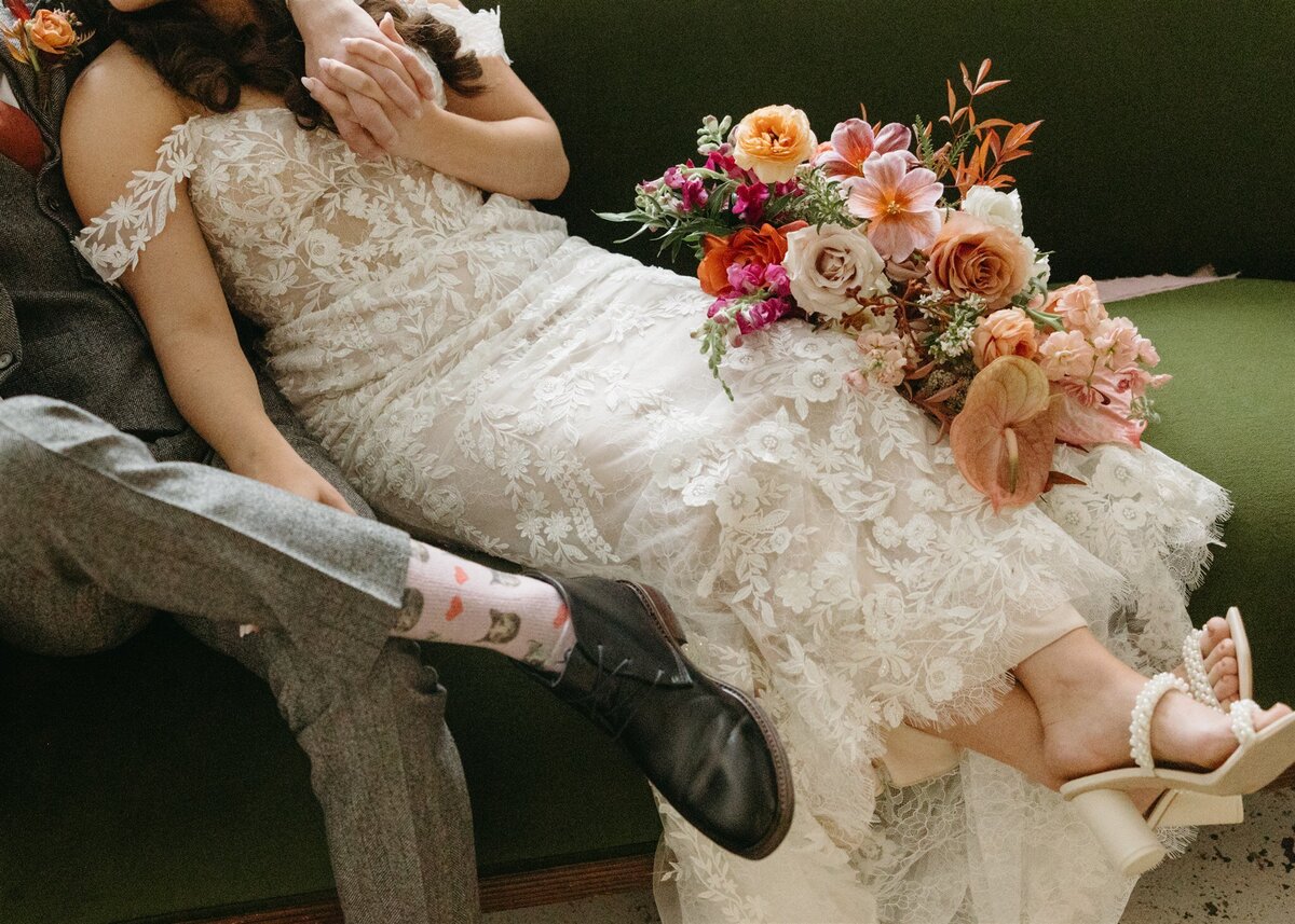 Bride wearing lace dress holding.a colorful bouquet with and groom at romantic spring wedding at the St vrain, Longmont wedding venue