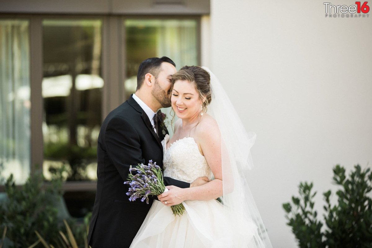 Groom whispers into Bride's ear as she smiles