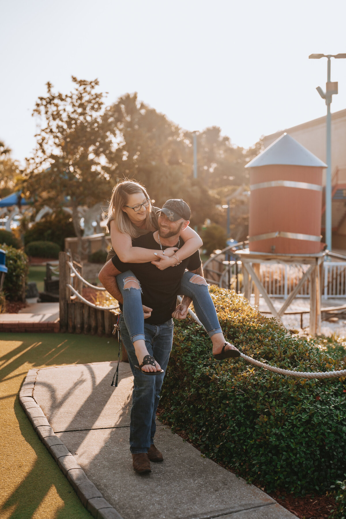man giving woman piggy back ride and laughing at eachother during engagement session