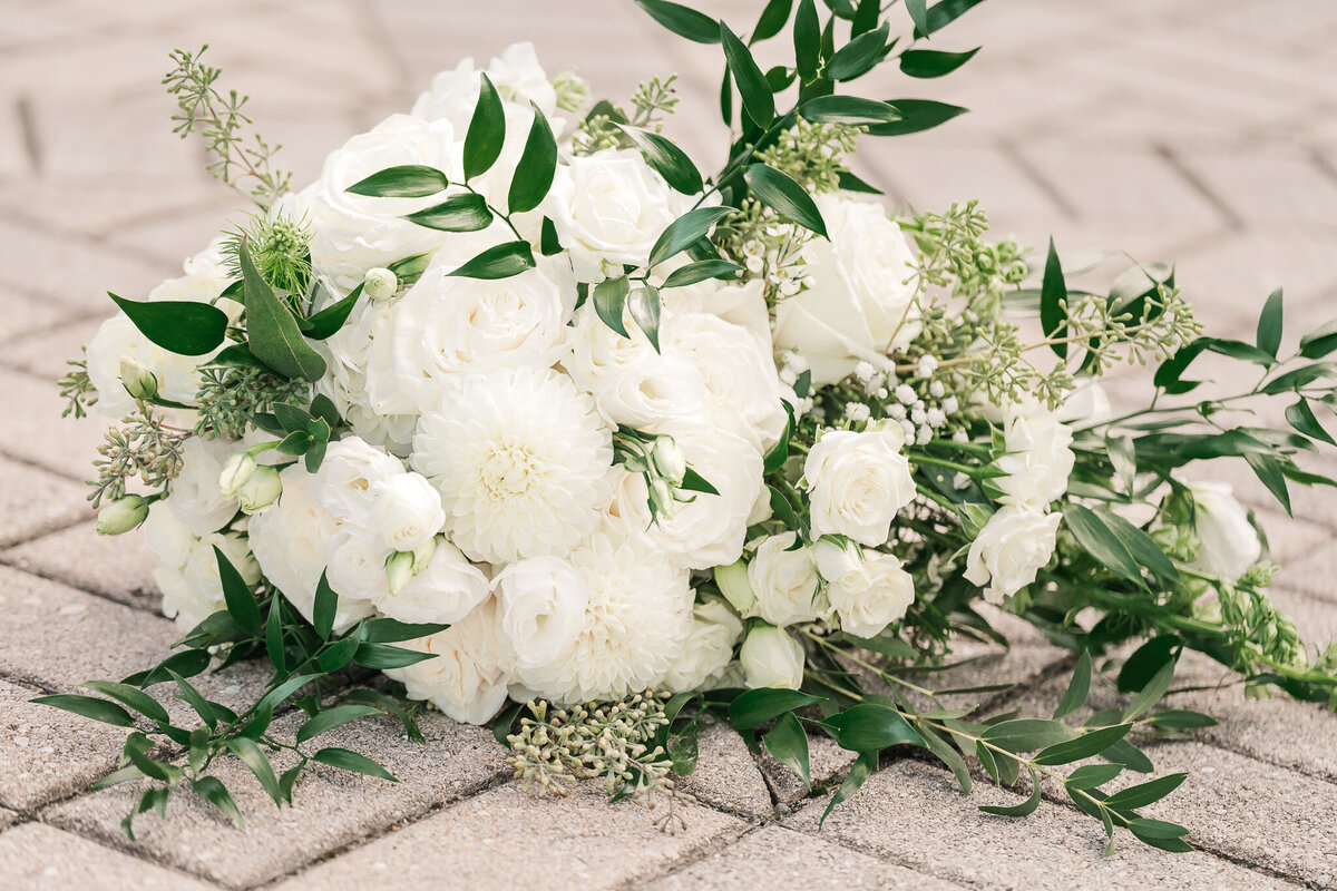 A white and green wedding bouquet laying on grey stone by JoLynn Photography, a Raleigh wedding photographer