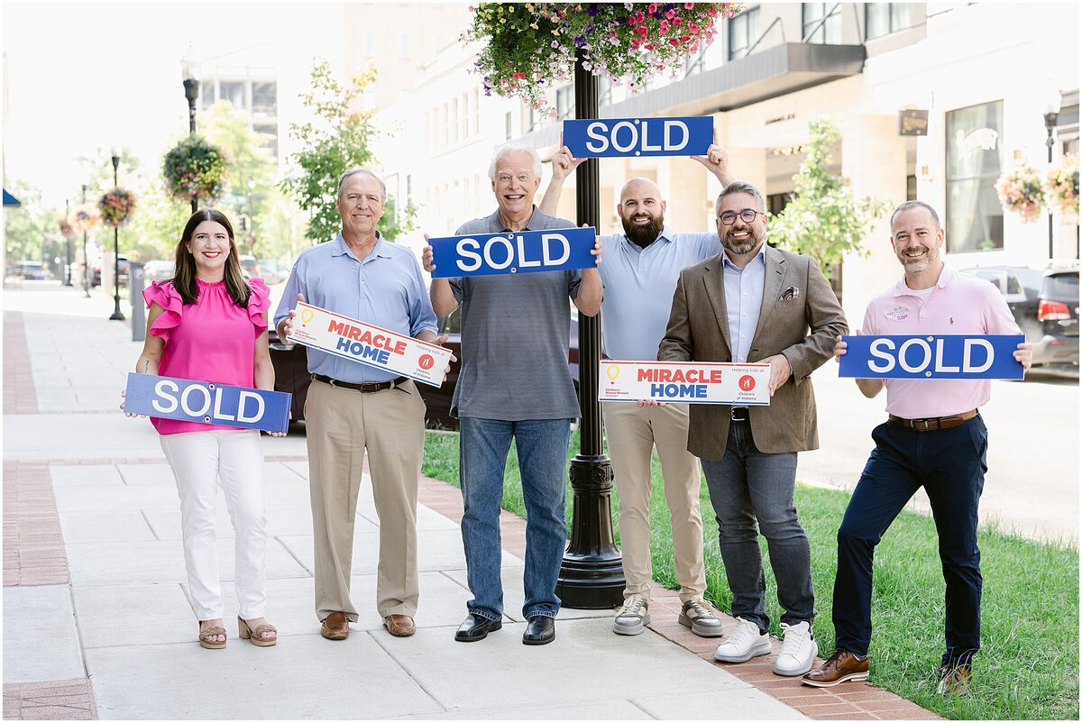 Real Estate agents posing with sold signs