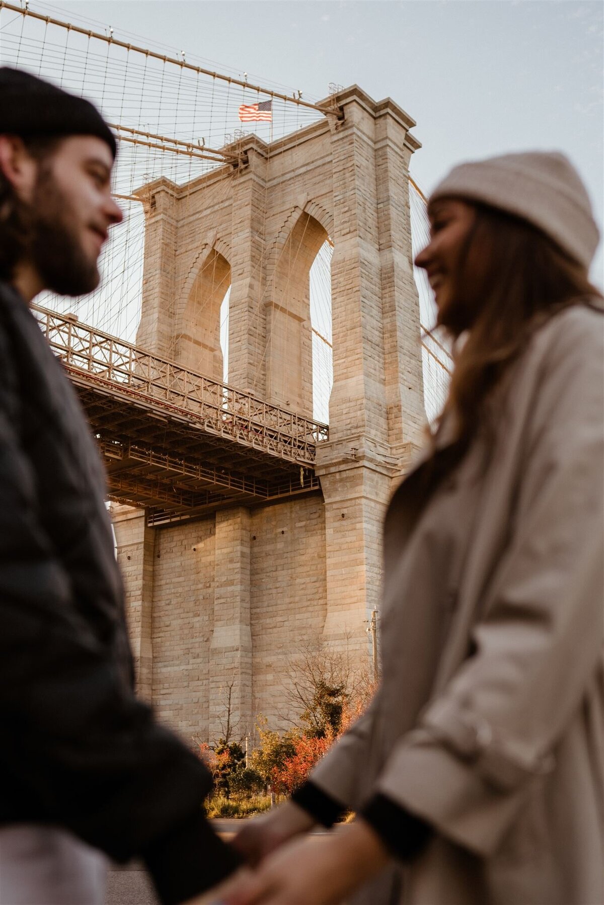 couple holding hands in front of nyc bridge