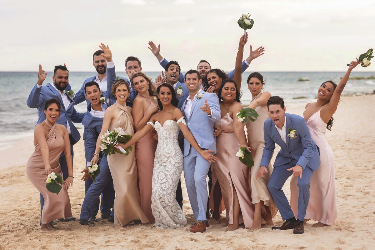 Bride, groom and bridal party having fun on beach at wedding in Riviera Maya