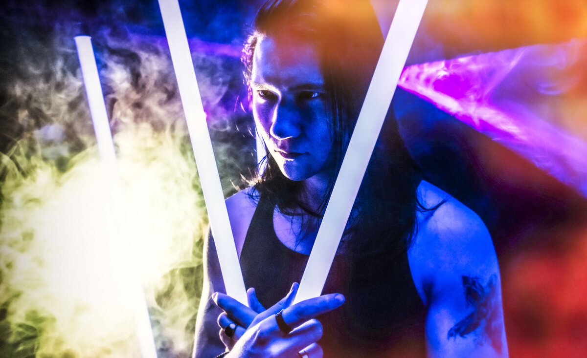Male musician portrait Sean Harper holding light tubes with colored smoke  surrounding