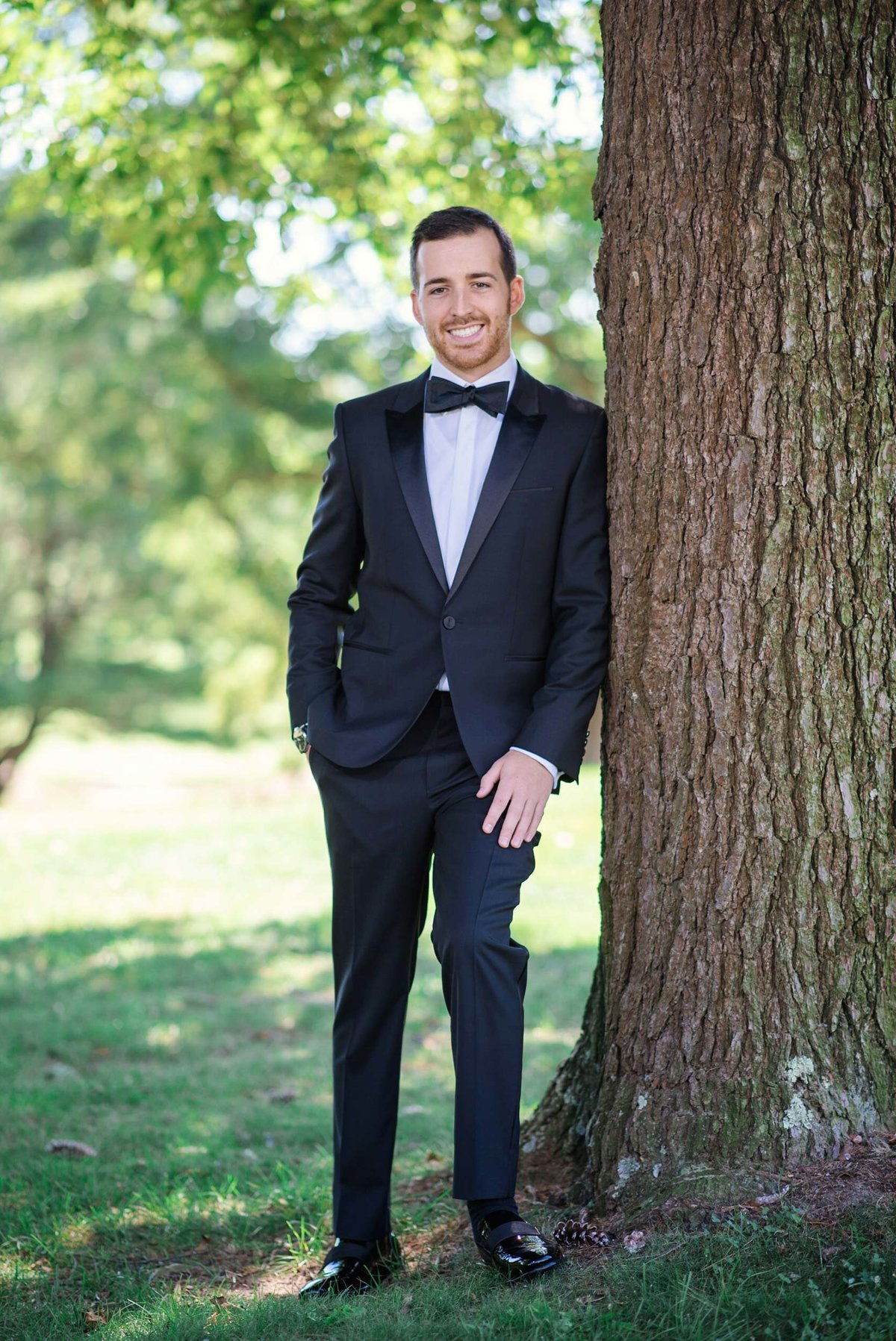 Groom alone leaning on tree outside at Stonebridge Country Club