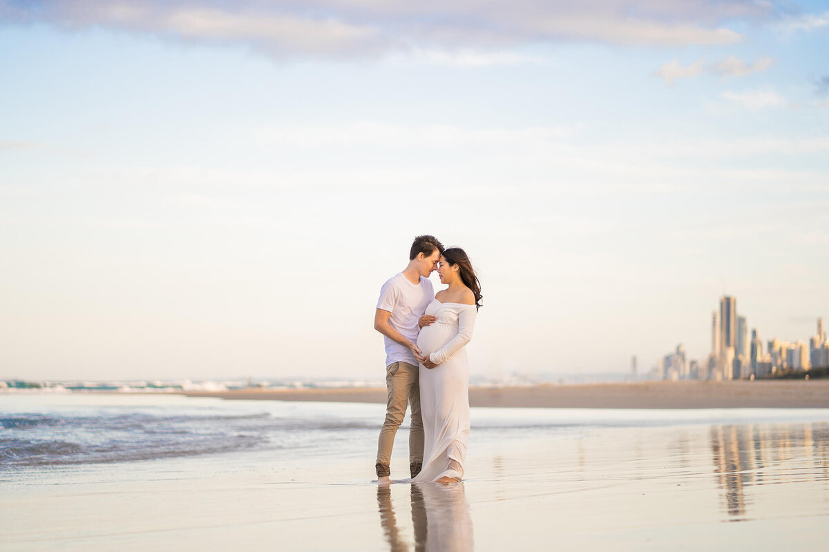 Pregnancy photos on the beach with Gold Coast skyline in background
