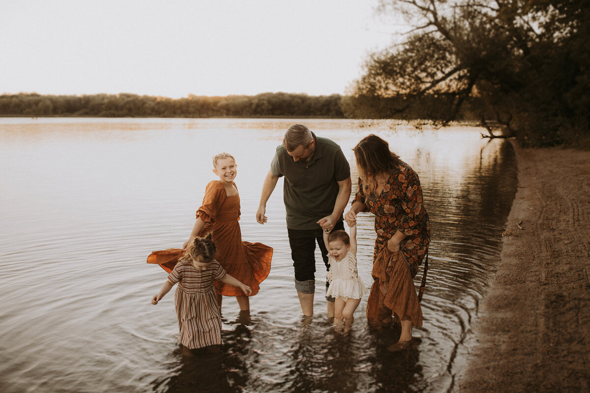 Family in pretty clothes spashing in a Kenosha lake at sunset.