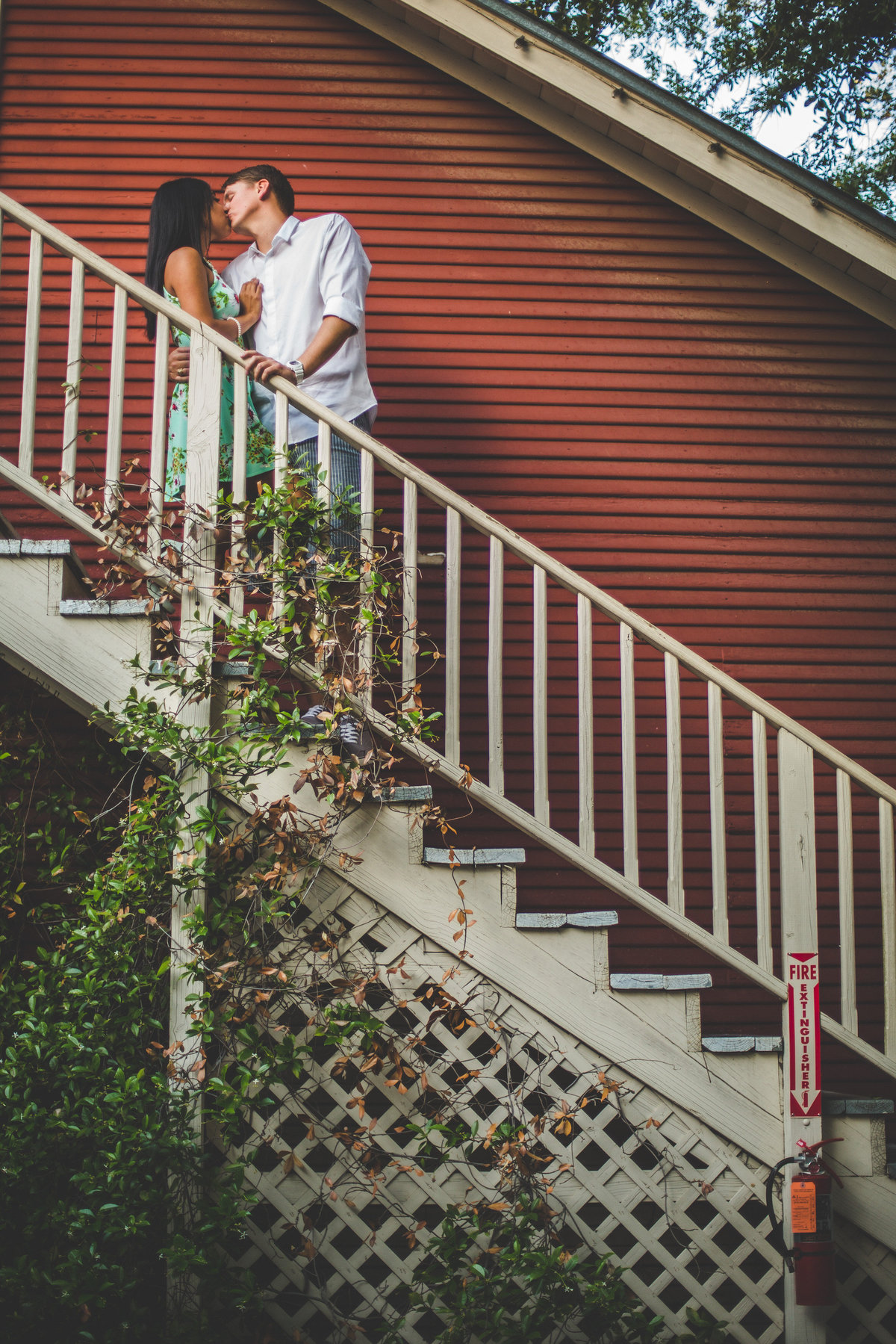 Couple kissing on the stairs at their engagement photography shoot at Ye Kendall Inn in Boerne, Texas.