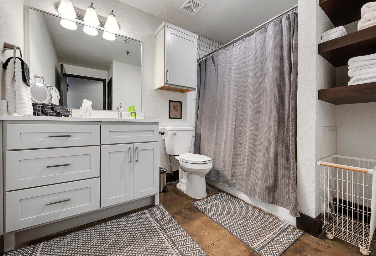 Bathroom with large vanity and shower in this one-bedroom, one-bathroom vintage industrial condo with Smart TV, free Wi-Fi, and washer/dryer located in downtown Waco, TX.