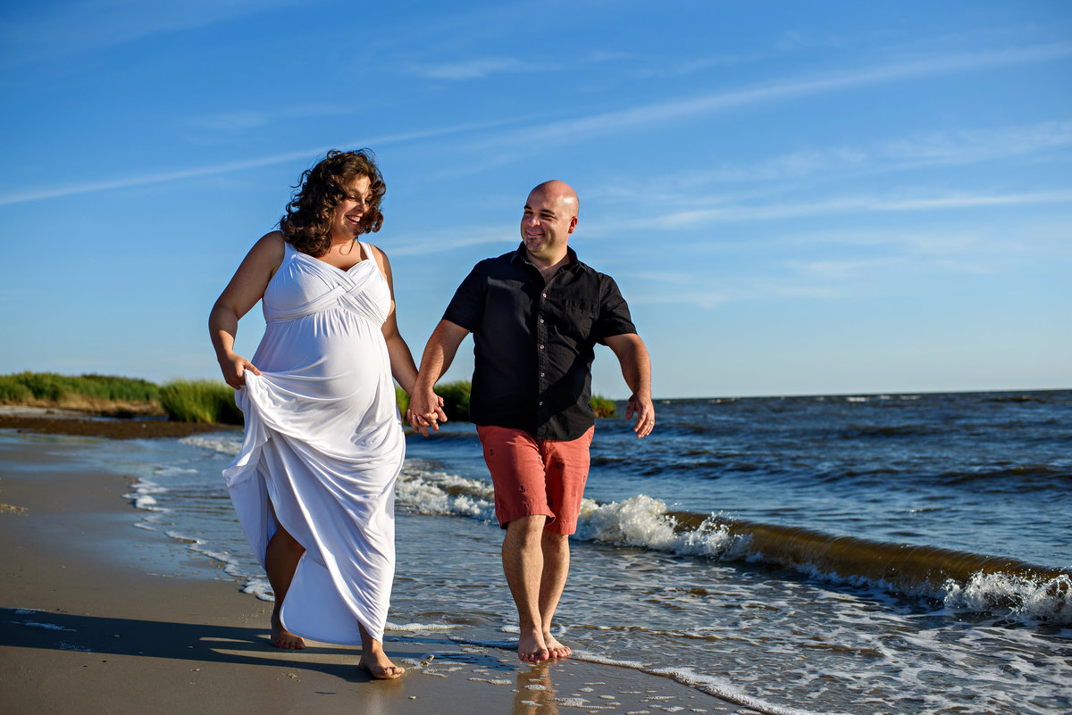 Parents to be walk along the beach in the water.