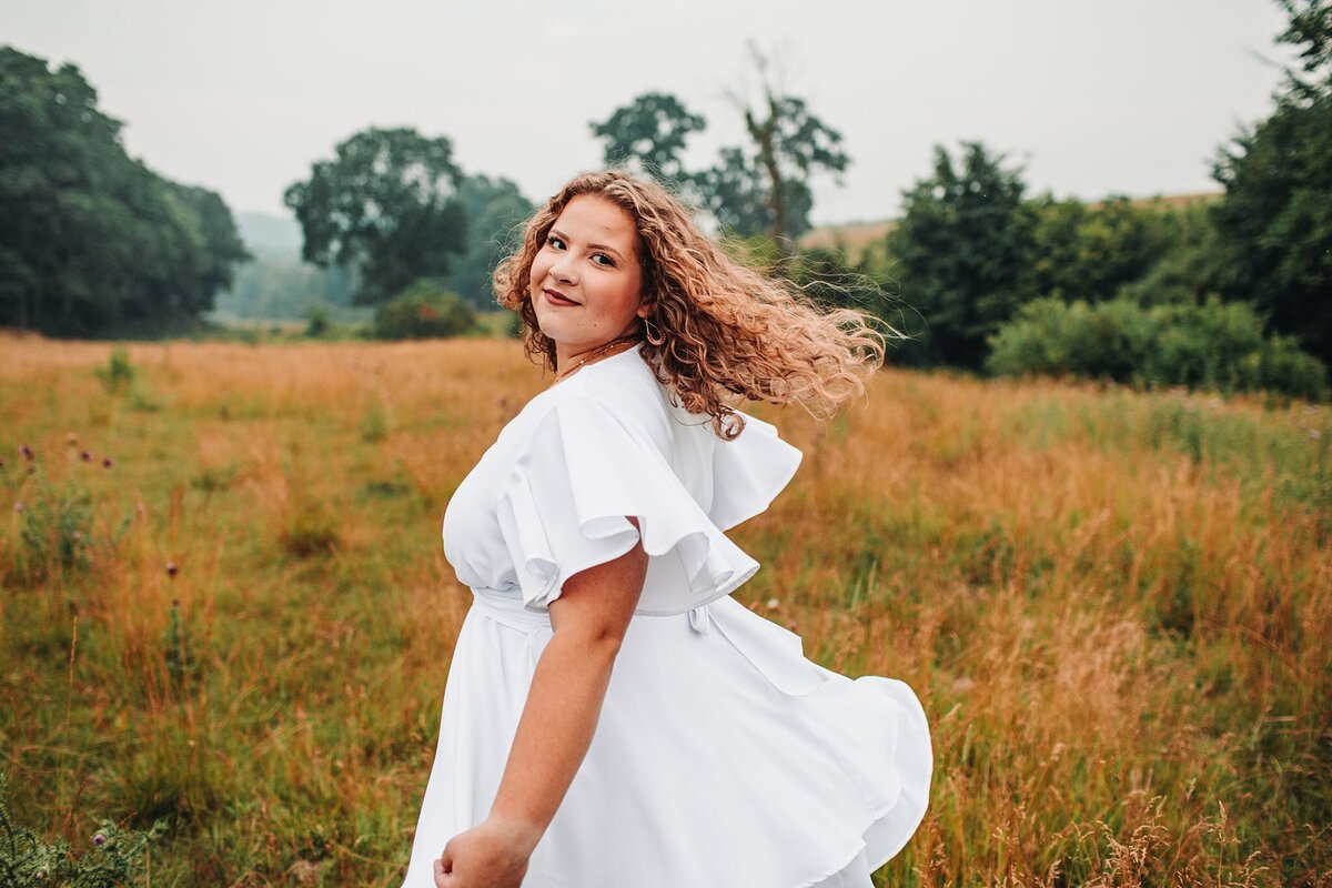 This high school senior is enjoying her senior photography experience  in the pasture