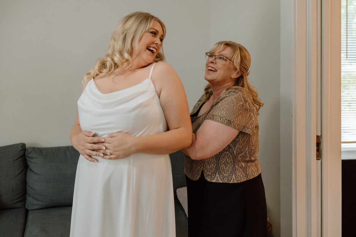 mother of the bride doing up her daughter's dress