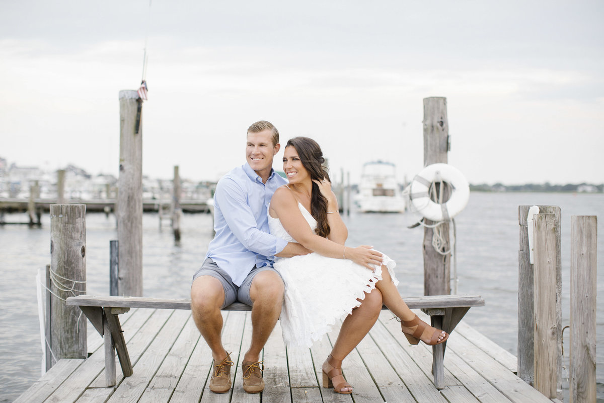 engaged couple sitting together on dock in sea bright