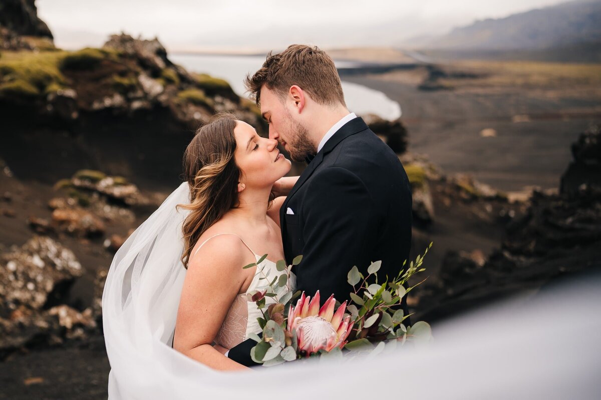 Sealed with a kiss against the stunning Icelandic coast, the couple embraces, the bride's long veil gracefully framing their love story.
