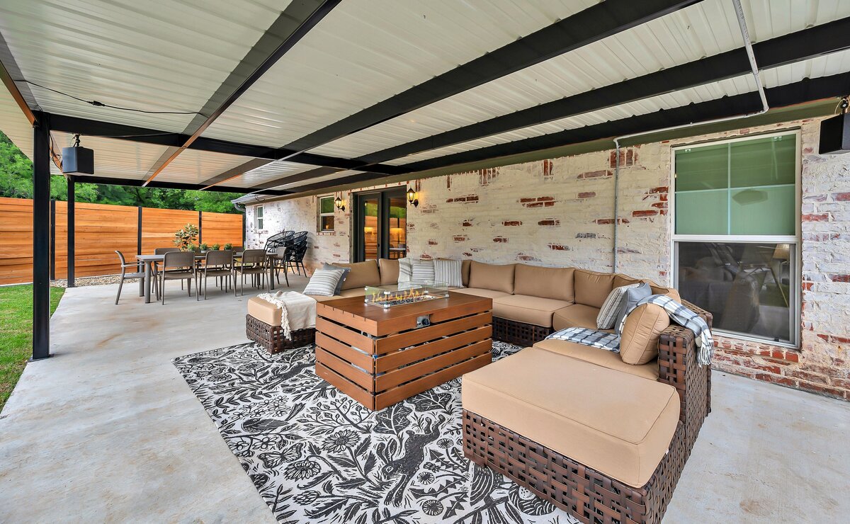 Spacious covered patio with plenty of seating in the backyard of this three-bedroom, three-bathroom vacation rental home with free wifi, outdoor theater, hot tub, propane grill and private yard in Waco, TX.