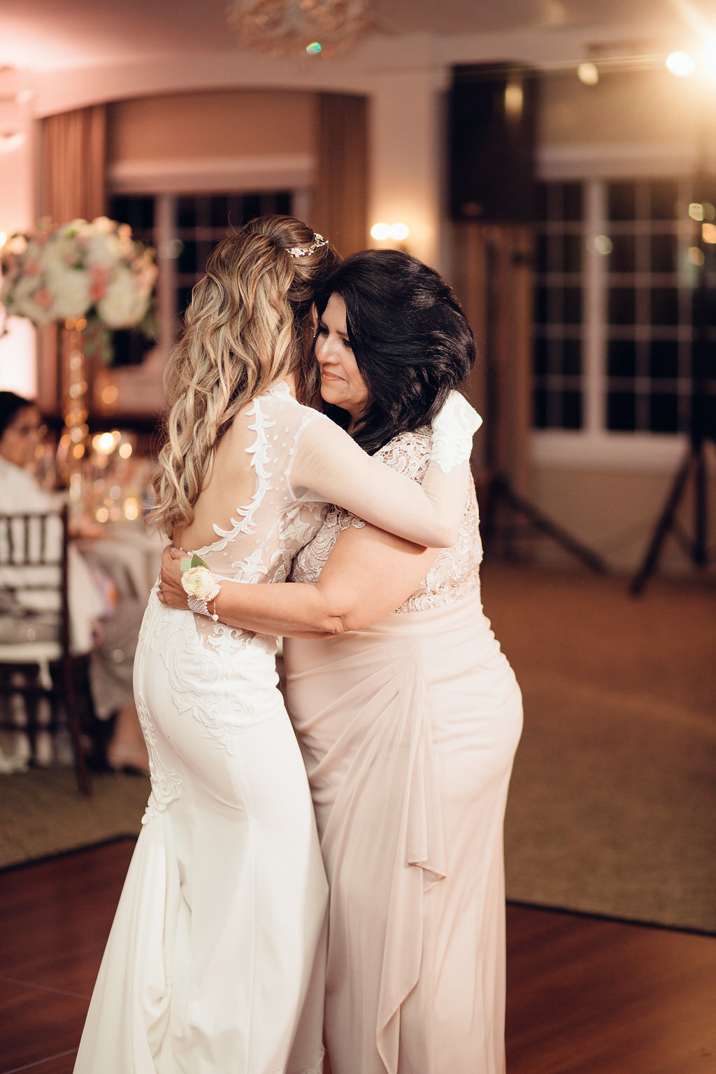 Wedding Photograph Of Woman In Light Brown Dress Hugging The Bride Los Angeles