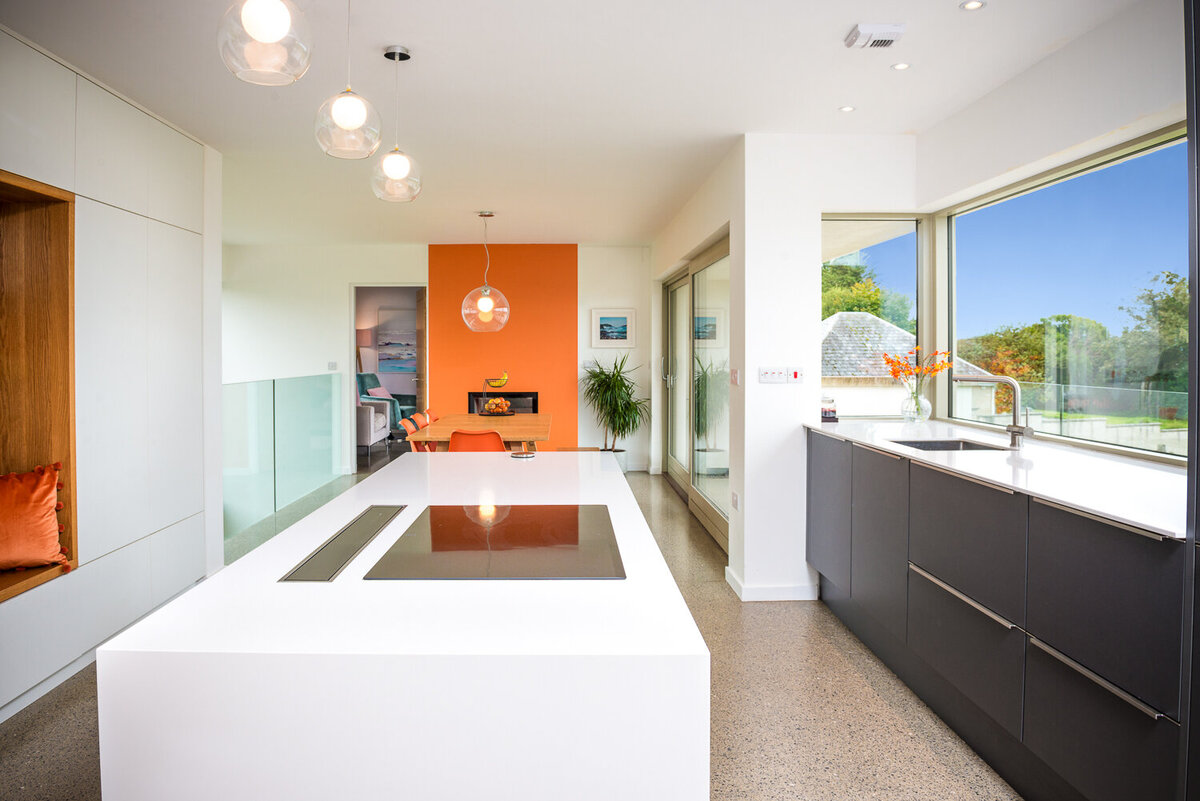 Modern kitchen with orange feature wall, island with cooker and grey kitchen units