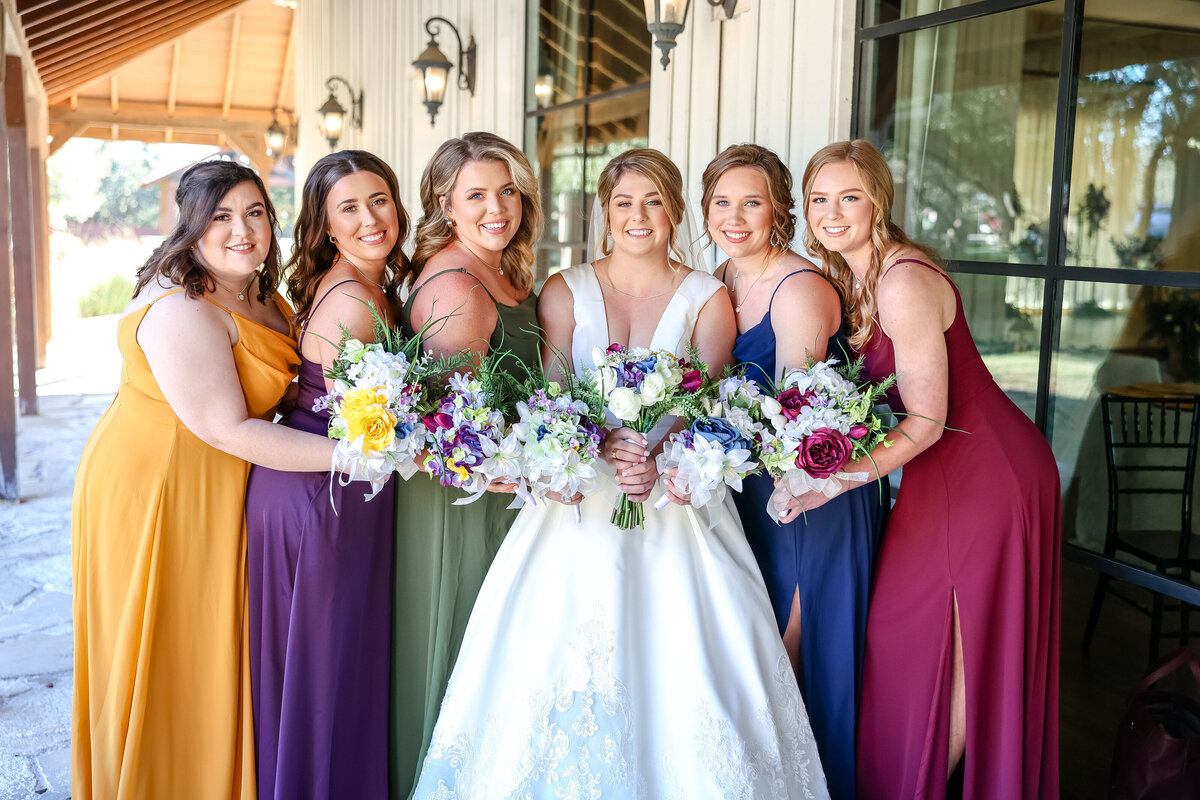 bridesmaids huddle together touching bouquets at wedding near Austin Texas