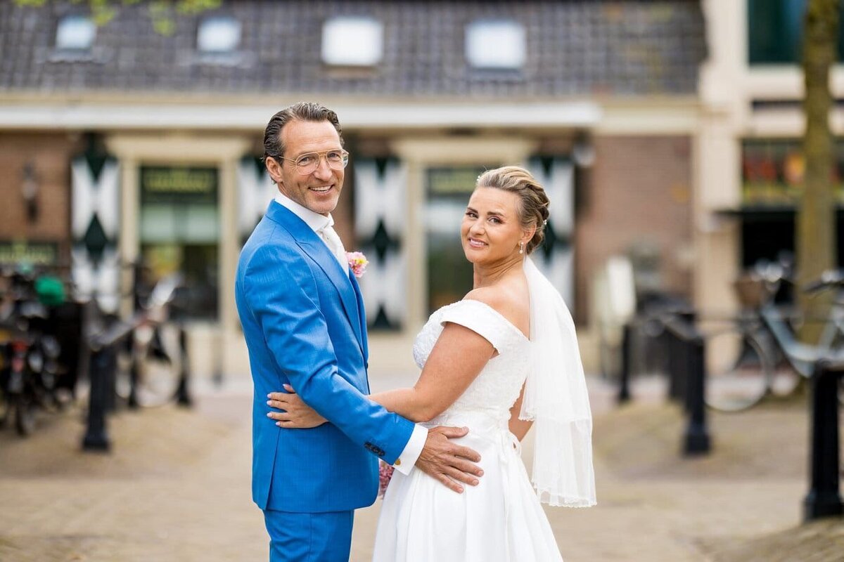 Bruidspaar kijkt samen achterom en houdt elkaar liefdevol vast tijdens hun bruiloft, georganiseerd door weddingplanner