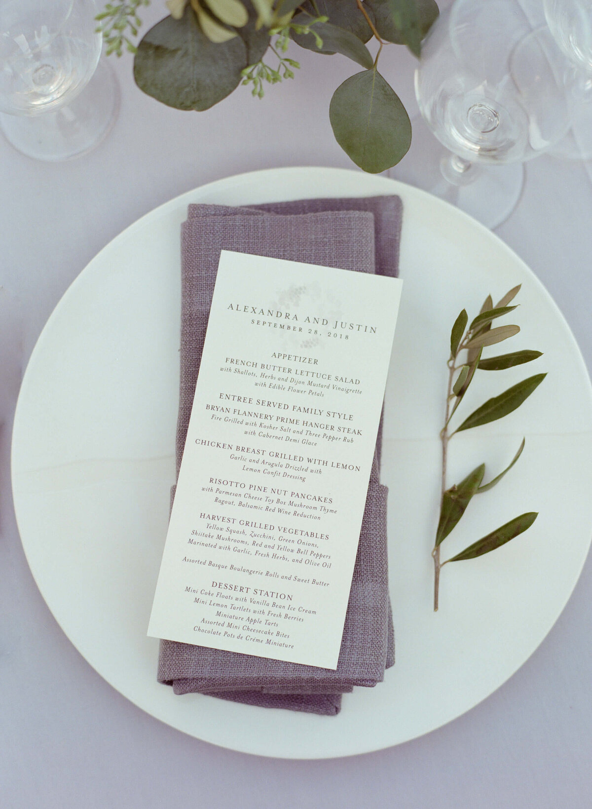 Three course wedding reception menu placed on a plate with a lavender napkin.