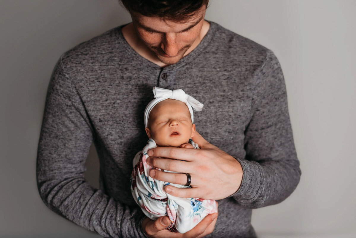 photo of man holding newborn on his chest