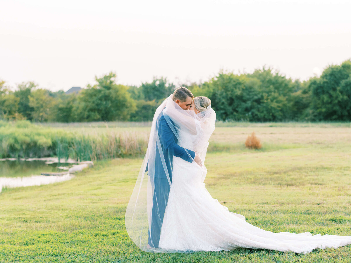 Bride and groom embrace wrapped in cathedral veil
