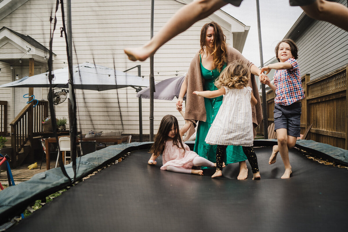 Mom and four kids jump on a trampoline during a family session in Chattanooga, TN.