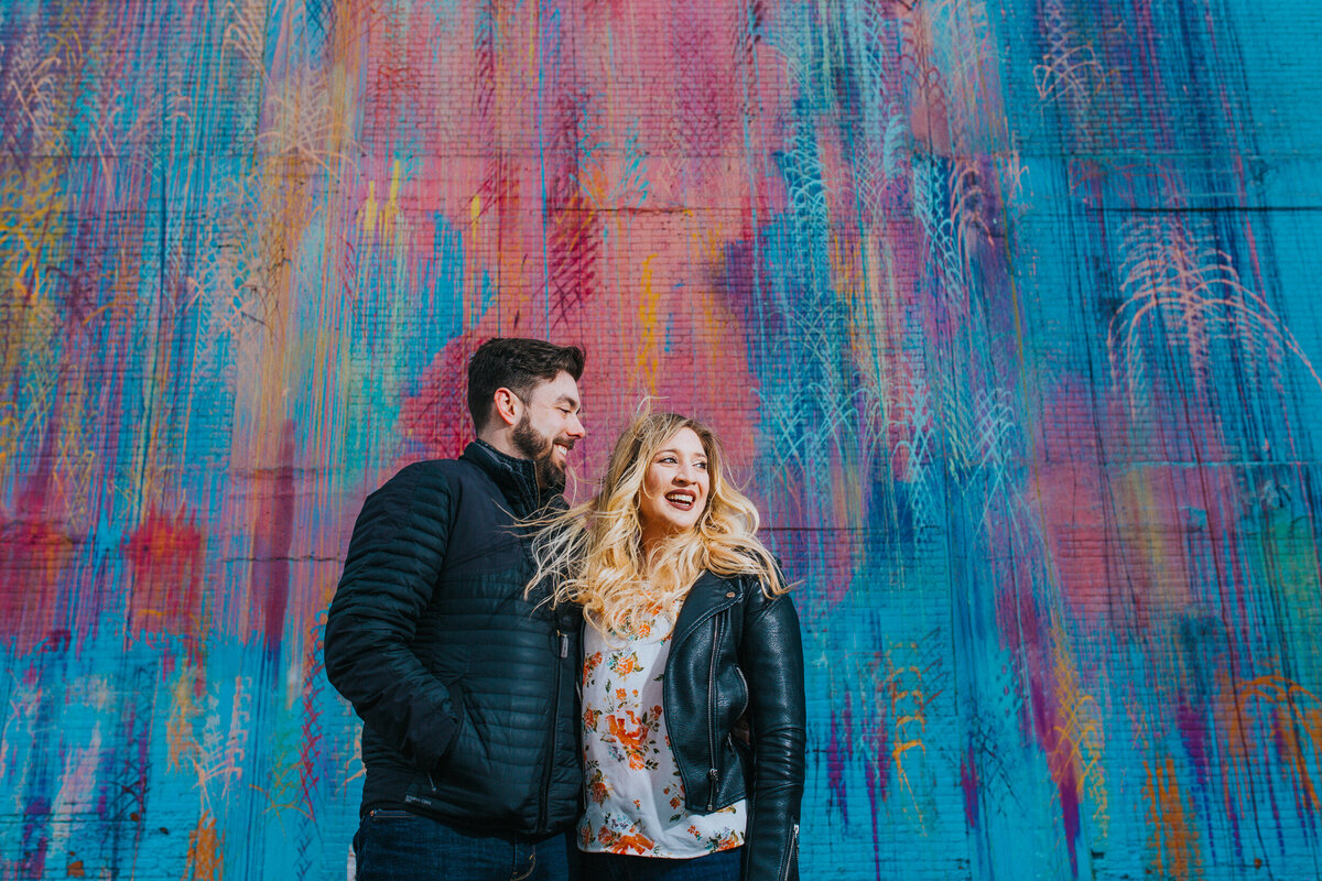 A winter engagement photo in front of a colorful detroit mural.  Photo By Adore Wedding Photography. Toledo Wedding Photographers